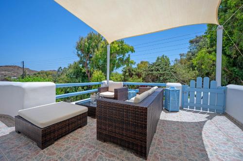 a patio with an umbrella and chairs and a table at Molos Sea View House - Paros Greece in Molos Parou