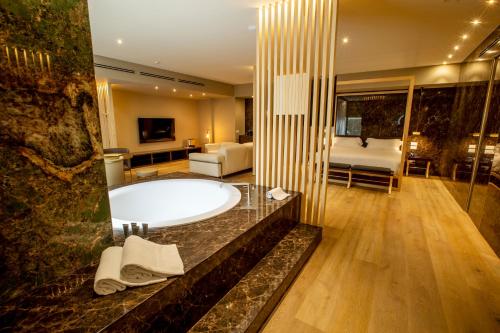 a bathroom with a bath tub and a bedroom at UNA HOTELS MH Matera in Matera
