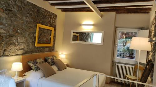 sypialnia z białym łóżkiem i kamienną ścianą w obiekcie Santa Marta Rooms - Vernazza w mieście Vernazza