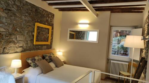 ein Schlafzimmer mit einem weißen Bett und einer Steinmauer in der Unterkunft Santa Marta Rooms - Via Del Santo 25 in Vernazza