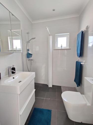 a white bathroom with a sink and a toilet at Casa Sequeira in Albufeira