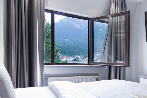 a bedroom with a window with a mountain view at Kayus in Buşteni