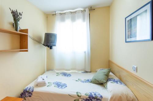 a small bedroom with a bed with a window at Apartamentos Maribel in Calaceite