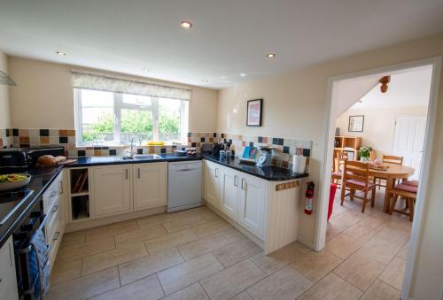 a large kitchen with white cabinets and a table at Avocet House in West Lulworth