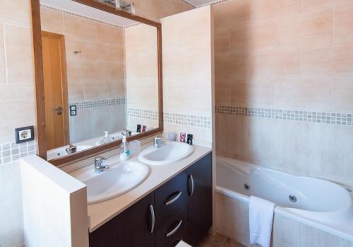 a bathroom with two sinks and a tub and a mirror at Apartamentos Maribel in Calaceite