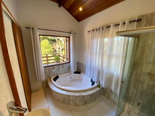 a large bathroom with a tub and a window at Chalé vale das Araucárias in Monte Verde