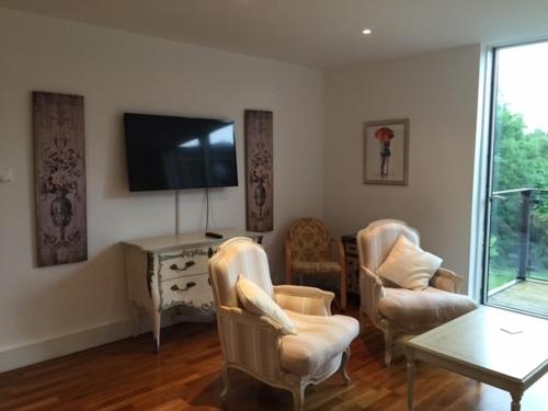 a living room with chairs and a tv and a table at City Centre Luxurious Cambridge 2 Bed Apartment with Balcony, Lift, Free Parking, Fast WIFI & Sleeps 6 in Cambridge