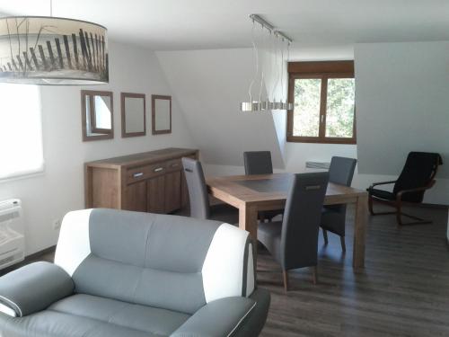 un salon avec une table, des chaises et un canapé dans l'établissement Appartement - Au Vieux Moulin, à Leulinghen-Bernes