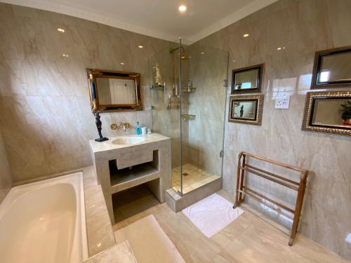 a bathroom with a shower and a sink and a tub at Goblin's Mead in Edgemead