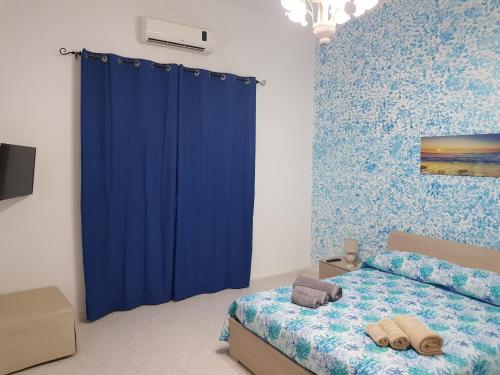 Un dormitorio con una cortina azul y una cama en Sea House, en Pozzallo