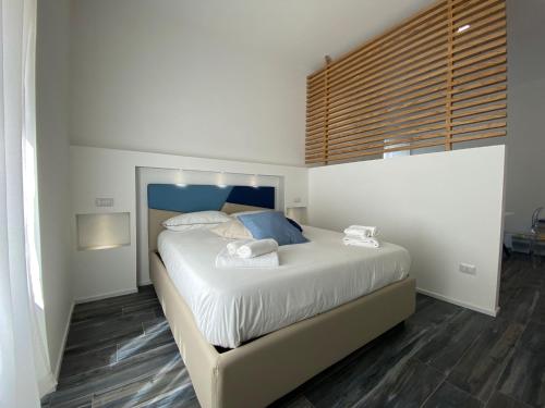 Schlafzimmer mit einem Bett mit weißer Bettwäsche und blauen Kissen in der Unterkunft Blue Bay Suite & Spa in Agropoli