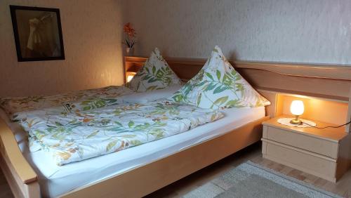 a bed with pillows and a lamp on a night stand at Annelieses Ferienwohnungen in Schneverdingen