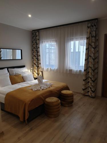 a bedroom with a large bed and two windows at Indium City Panzió in Eger