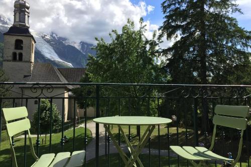 een balkon met een tafel en stoelen en een kerk bij Flat Near The Slopes Chamonix Mont Blanc in Chamonix-Mont-Blanc