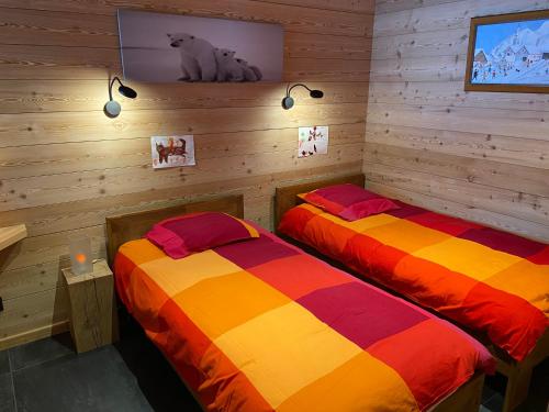 two beds in a room with wooden walls at Chalet Serre Chevalier in Le Monêtier-les-Bains