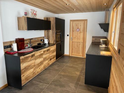 une cuisine avec des comptoirs noirs et des armoires en bois dans l'établissement Chalet Serre Chevalier, au Monêtier-les-Bains