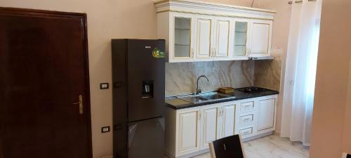 cocina con armarios blancos y nevera negra en Hotel Dragoi, en Velipojë