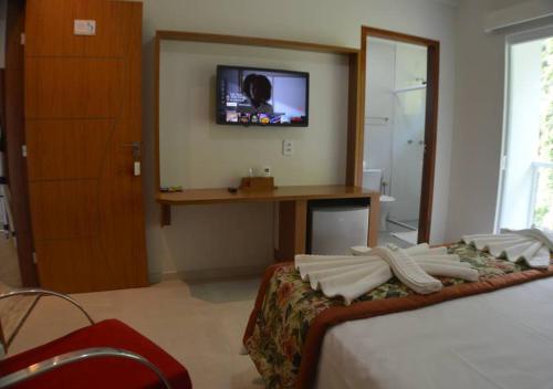 a bedroom with a bed with a tv on the wall at Pousada Cantinho da Praia in Paraty