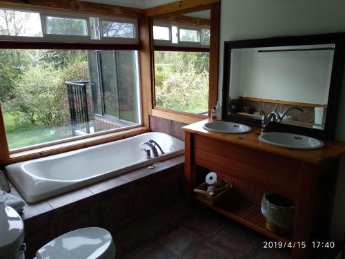 a bathroom with a tub and two sinks and a mirror at Harrison Hammond House Farmstay in Harrison Mills