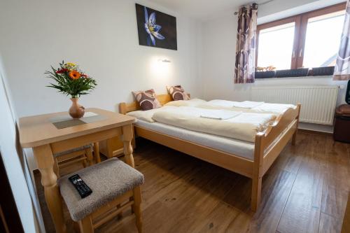 a bedroom with a bed and a table with a vase of flowers at Penzion Kamzik a Drevenica in Habovka