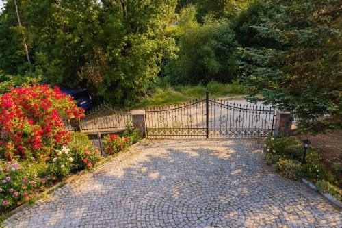a metal gate in a garden with flowers at Mira - Mira pokoje z widokiem na jezioro in Chmielno