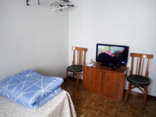 1 dormitorio con 1 cama, TV y 2 sillas en VALLADOLId, en Valladolid
