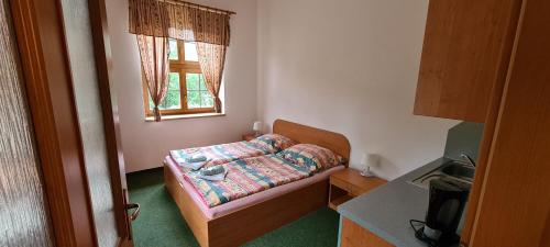 a small bedroom with a bed and a window at Horské ubytování Královský dvůr na Bílém potoce in Hamry