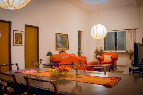 a living room with a table and orange chairs at Hotel Solar dos Tchuccos in Uruguaiana