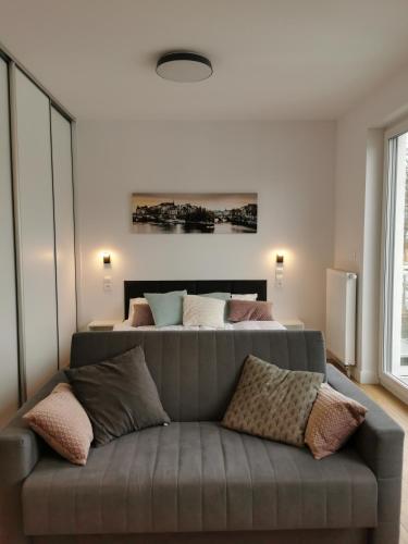 a living room with a couch in front of a bed at Apartamenty Garbary 32 z klimatyzacja - air-conditioning in Poznań