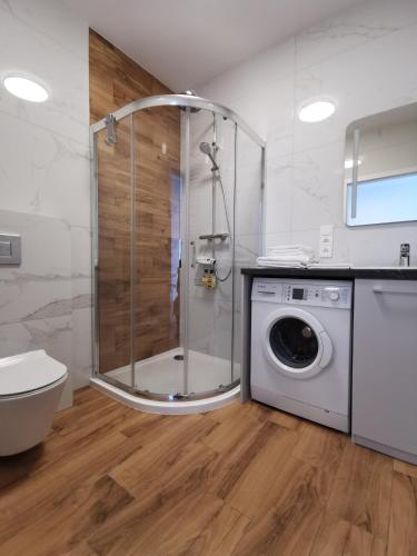 a bathroom with a shower and a washing machine at Apartamenty Garbary 32 z klimatyzacja - air-conditioning in Poznań