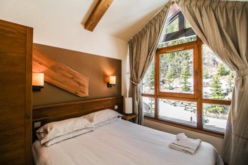 um quarto com uma cama grande e uma janela em Charming 6th-floor 2-bedroom apartment with fireplace em Flaine