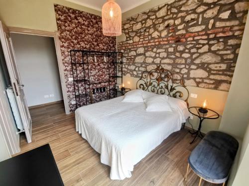 - une chambre avec un lit blanc et un mur en pierre dans l'établissement La Luna dei Medici, à Fivizzano