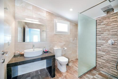 bagno con servizi igienici, lavandino e specchio di Villa Pines a Limenaria