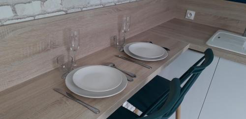 uma mesa com pratos brancos e copos de vinho em Studio Confort Lorient Rue Vauban Hypercentre em Lorient