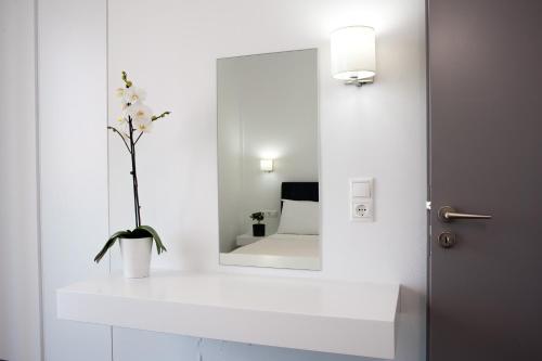a bathroom with a mirror and a vase with a flower at Aestas Apartments in Agia Marina Nea Kydonias