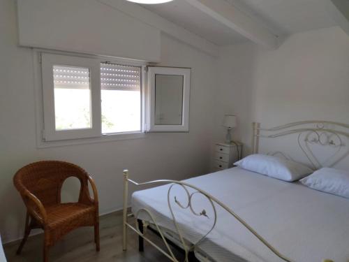 ein Schlafzimmer mit einem Bett und einem Stuhl sowie zwei Fenstern in der Unterkunft Dimora Arnesano in Torre Lapillo