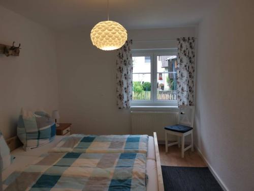 a bedroom with a bed and a window and a chandelier at Ferienwohnung Ramona - idyllisch und charmant in Kirchdorf im Wald