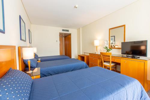 a hotel room with two beds and a television at MS Vila Nova in Ponta Delgada