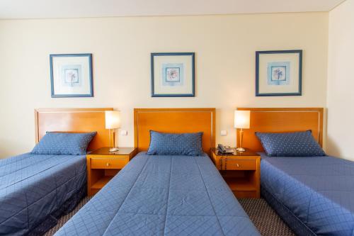 two beds in a hotel room with blue beds at MS Vila Nova in Ponta Delgada