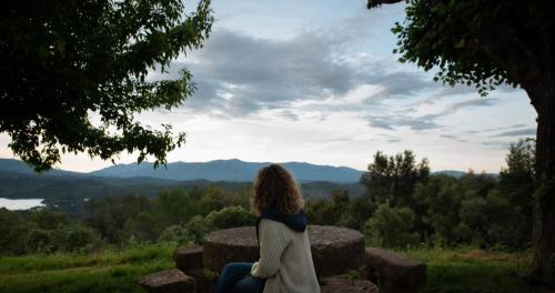a woman sitting on a rock looking at the mountains at Hostal la Salut de Terrades in Terrades