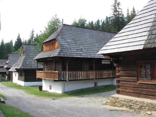 a group of wooden buildings with trees in the background at Penzion Kamzik a Drevenica in Habovka