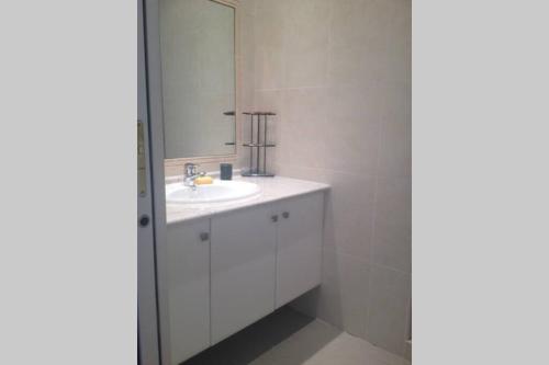 a white bathroom with a sink and a mirror at Location 2 pièces , avec piscine à partager in Les Adrets de l'Esterel