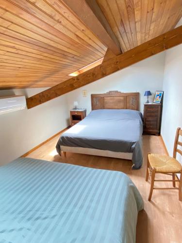 une chambre avec deux lits et un plafond en bois dans l'établissement Villa Climatisée et Wifi Gujan à 5 mn du Bassin d'Arcachon, à Gujan-Mestras