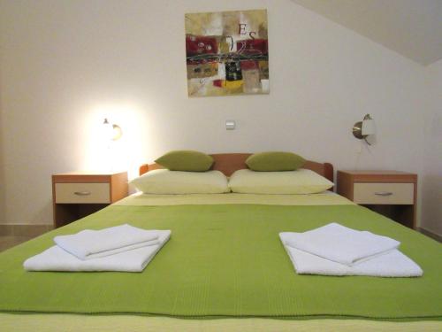 a large green bed with two white towels on it at Apartments Luna in Tisno