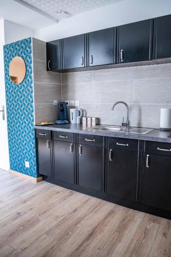 - une cuisine avec des placards noirs et un évier dans l'établissement CUDJOE, à Dinan