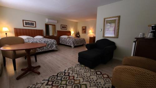 Cette chambre d'hôtel comprend deux lits, une table et des chaises. dans l'établissement Bouctouche Bay Inn, à Bouctouche