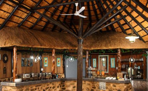 a restaurant with a bar with a straw roof at Ndalo Lodge Mbombela in Nelspruit