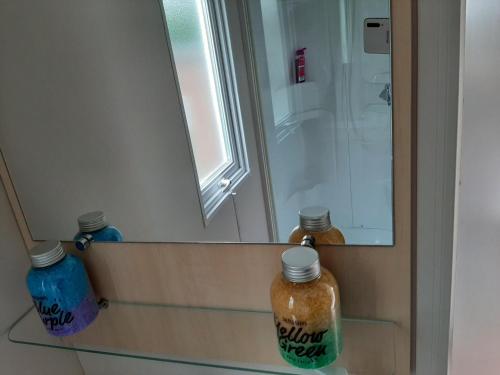 カルナックにあるCARNAC CAMPINGのバスルーム(鏡、棚にボトル2本付)