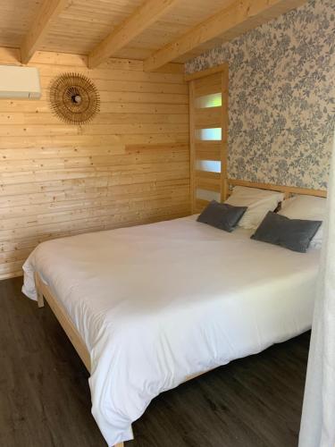 a bedroom with a large white bed in a wooden wall at Chambre privée avec accès piscine in Laouque