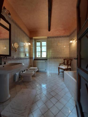 a bathroom with two toilets and a tub and a sink at Cascina Bolichin in Rodello